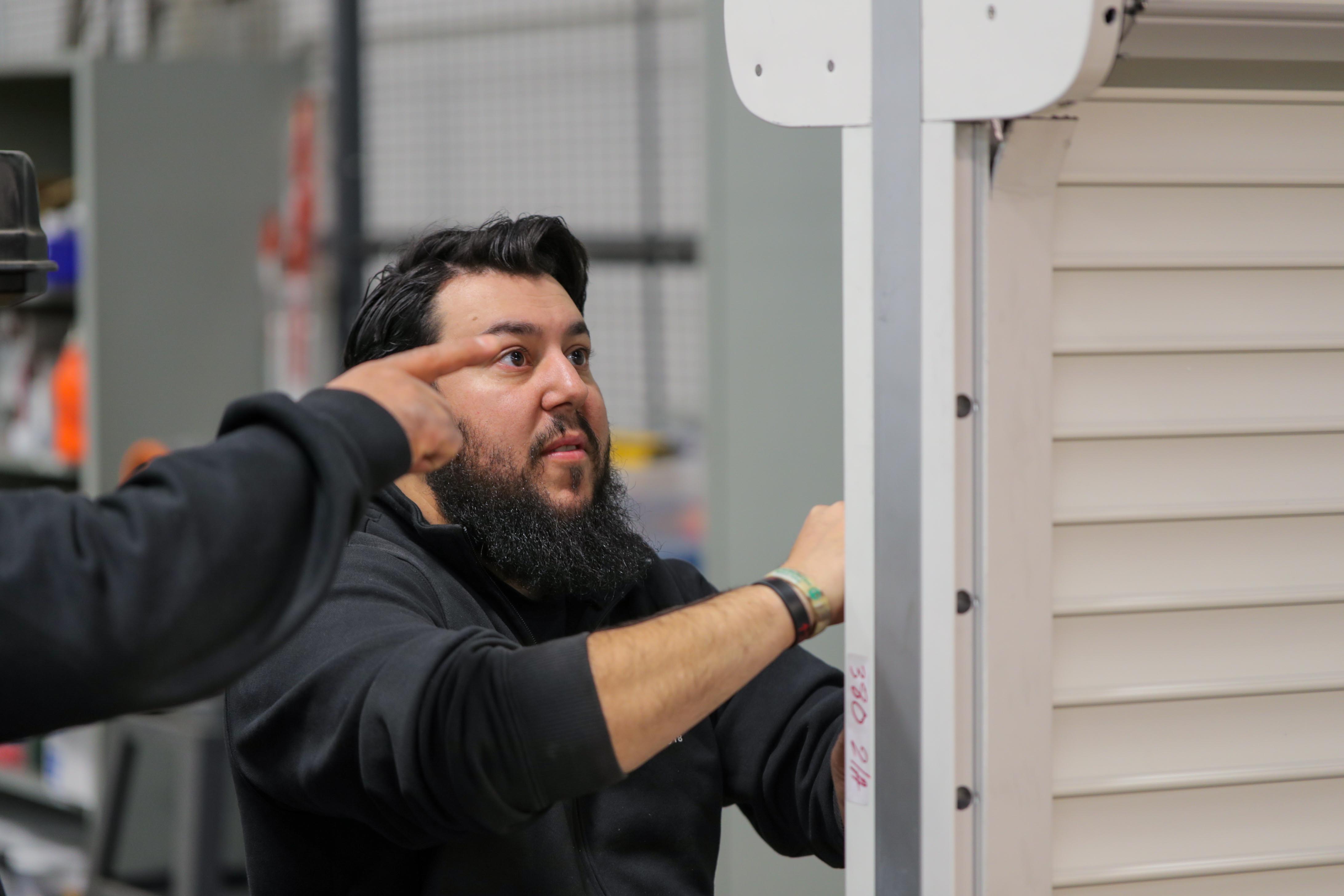 man is seen in a laboratory or workshop environment, examining the durability and functionality of the shutters.