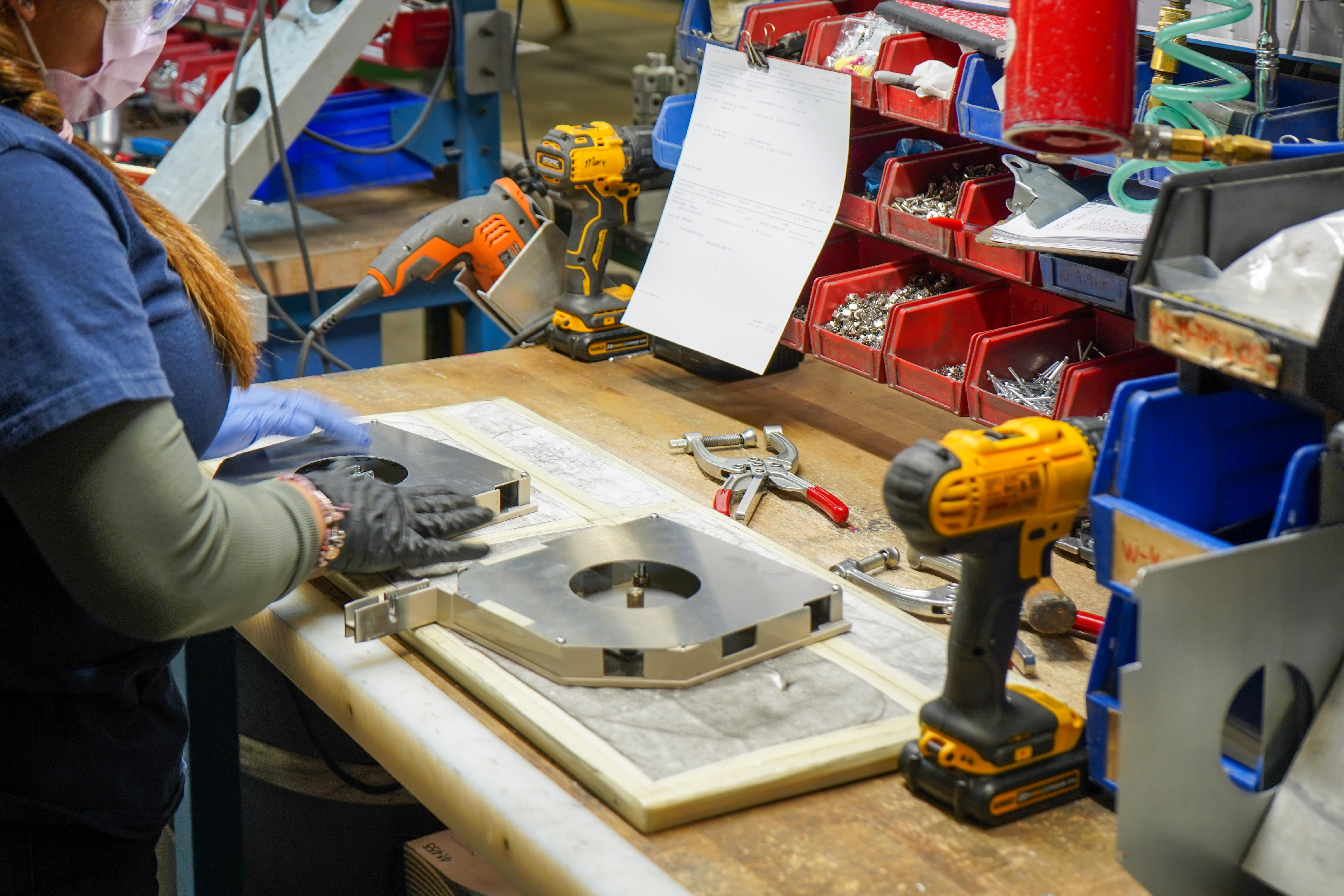 Image showing a person in a manufacturing facility, operating machinery to fabricate a metal piece.