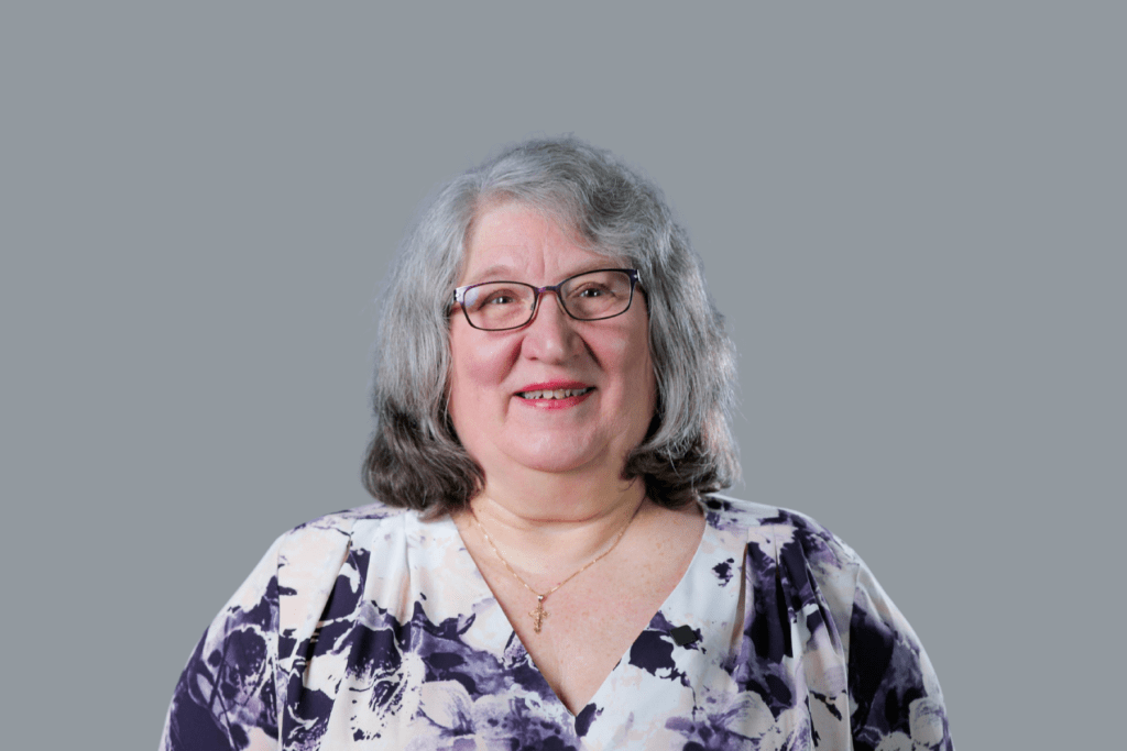 woman with glasses wearing a purple floral shirt