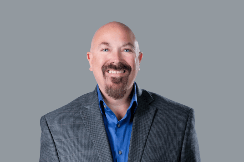 man with beard wearing a gray blazer and blue shirt