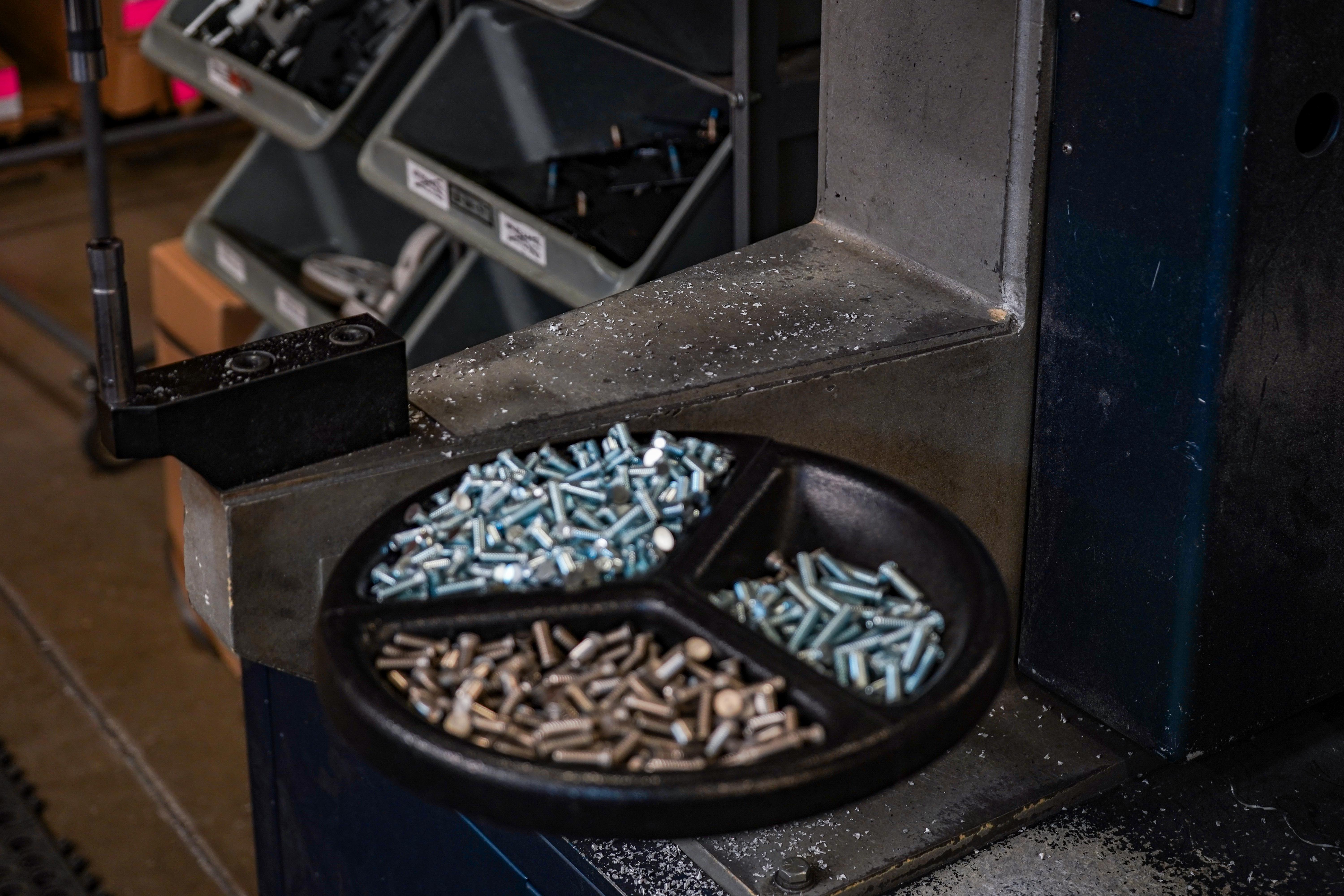 An assortment of nuts, bolts, and screws neatly arranged in a bowl, showcasing various sizes and shapes of metallic hardware.