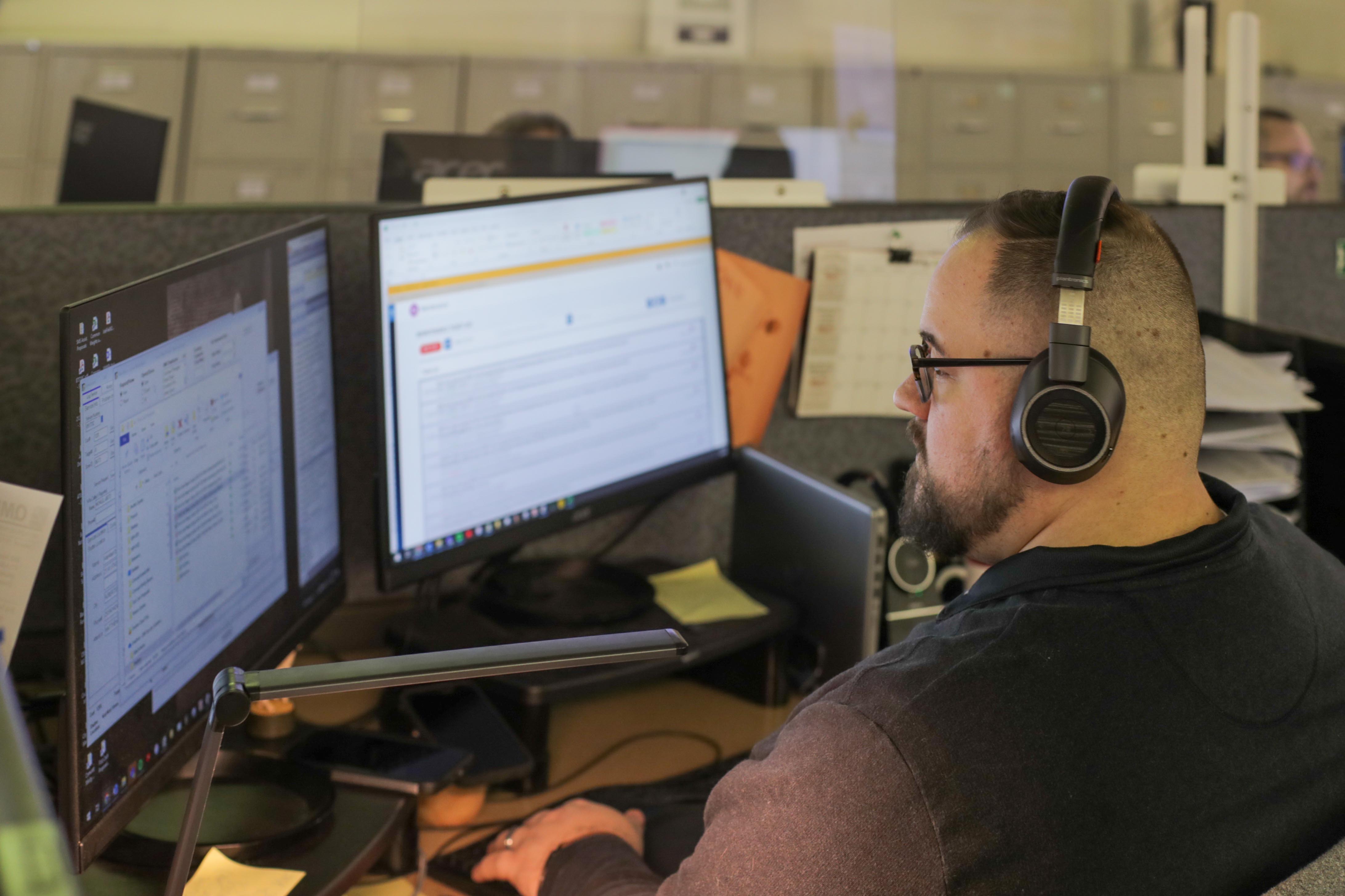 man working on computer with headset on