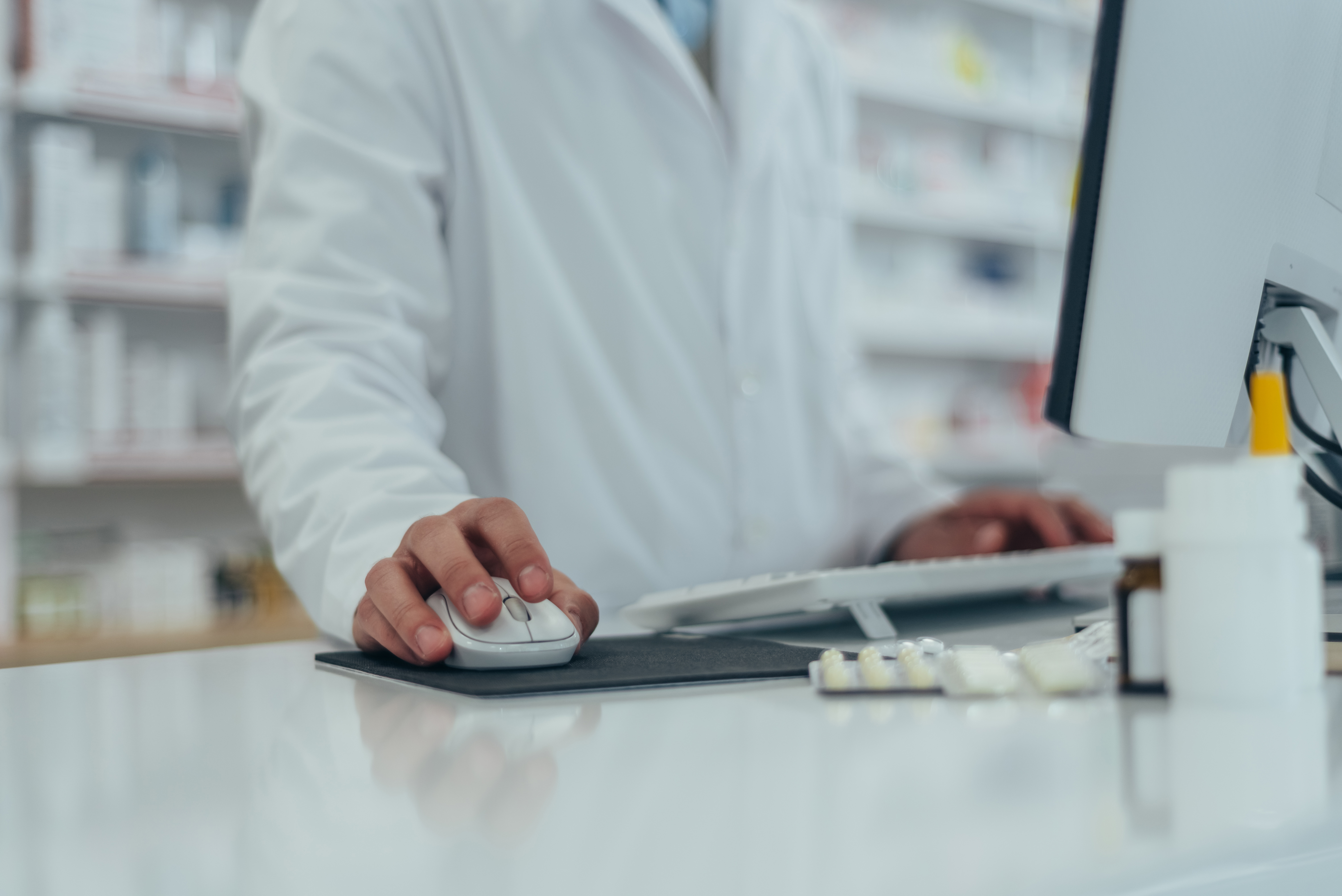 Close shot of pharmacist working in a pharmacy while using a com